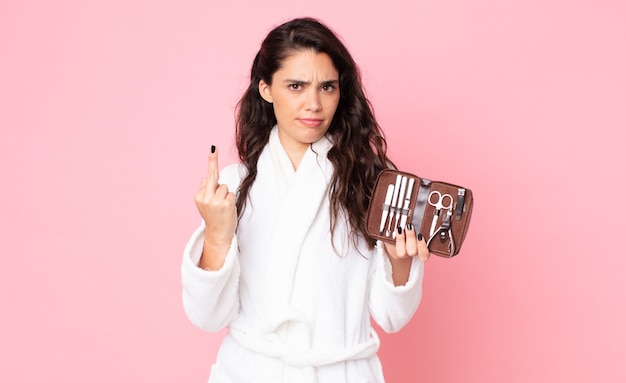 Mujer bonita que se siente enojada, molesta, rebelde y agresiva y sosteniendo una bolsa de maquillaje con herramientas de uñas