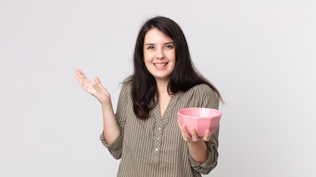 Mujer bonita que se siente feliz y asombrada por algo increíble sosteniendo un cuenco de olla vacío. agente asistente con un auricular