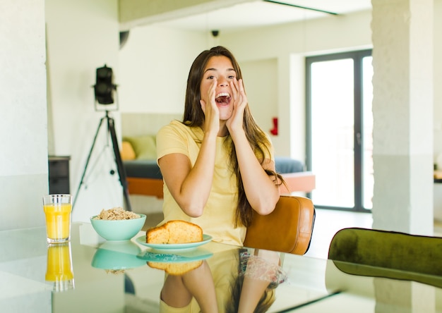 Mujer bonita que se siente feliz, emocionada y positiva, dando un gran grito con las manos al lado de la boca, gritando