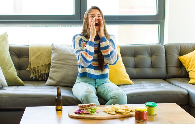 Mujer bonita que se siente feliz, emocionada y positiva, dando un gran grito con las manos al lado de la boca, gritando