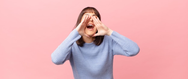 mujer bonita que se siente feliz, emocionada y positiva, dando un gran grito con las manos junto a la boca, gritando