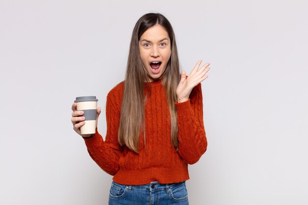 Mujer bonita que se siente feliz, emocionada, sorprendida o consternada, sonriendo y asombrada por algo increíble