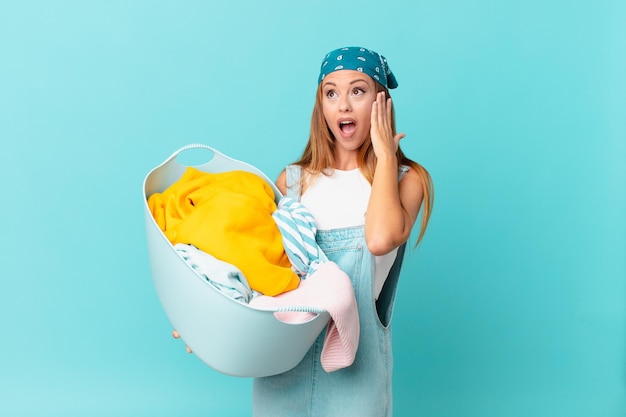 Mujer bonita que se siente feliz, emocionada y sorprendida sosteniendo una canasta de lavado