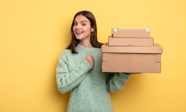 Foto mujer bonita que se siente feliz y enfrenta un desafío o celebra el concepto de cajas de paquetes