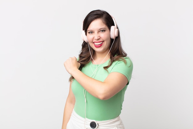 Mujer bonita que se siente feliz y enfrenta un desafío o celebra escuchando música con auriculares