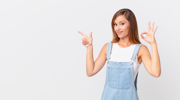 Mujer bonita que se siente feliz, mostrando aprobación con un gesto aceptable y un espacio de copia a un lado