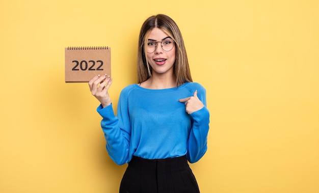 Mujer bonita que se siente feliz y se señala a sí misma con un emocionado concepto de calendario 2022