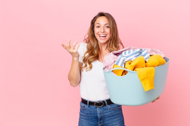 Mujer bonita que se siente feliz, sorprendida al darse cuenta de una solución o idea y lavar la ropa.