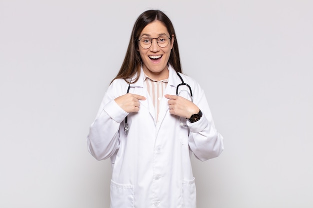 Mujer bonita que se siente feliz, sorprendida y orgullosa, señalando a sí misma con una mirada emocionada y asombrada