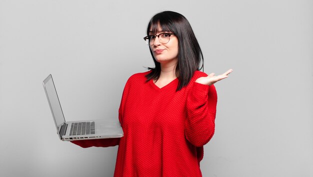 Mujer bonita que se siente perpleja y confundida, dudando, ponderando o eligiendo diferentes opciones con expresión divertida