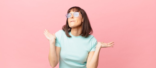 Mujer bonita que se siente perpleja y confundida, dudando, ponderando o eligiendo diferentes opciones con expresión divertida