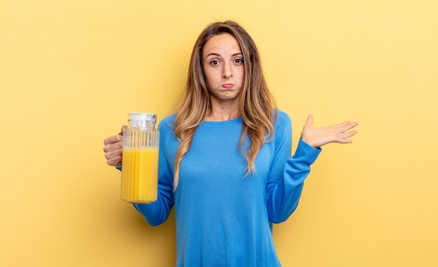 Mujer bonita que se siente perpleja y confundida y que duda del concepto de jugo de naranja