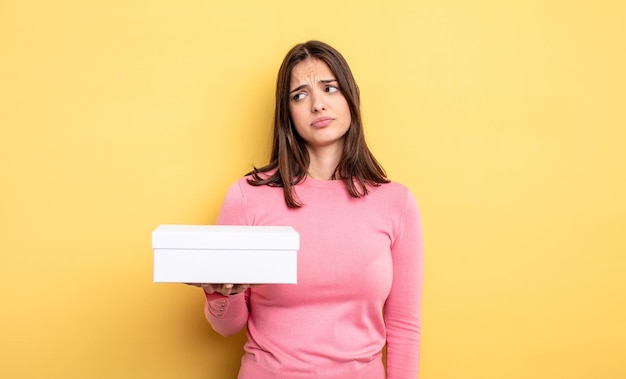 Mujer bonita que se siente triste, molesta o enojada y mira hacia el concepto de empaque de caja blanca lateral