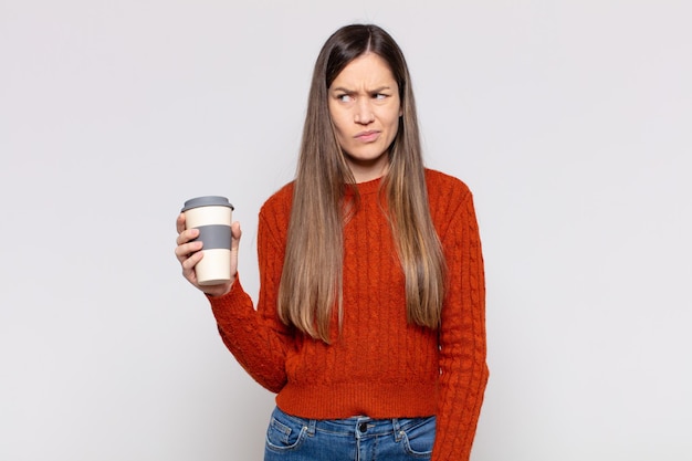 Mujer bonita que se siente triste, molesta o enojada y mira hacia un lado con una actitud negativa, frunciendo el ceño en desacuerdo