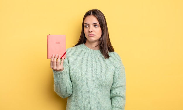 Mujer bonita que se siente triste, molesta o enojada y mira hacia un lado. concepto de planificador