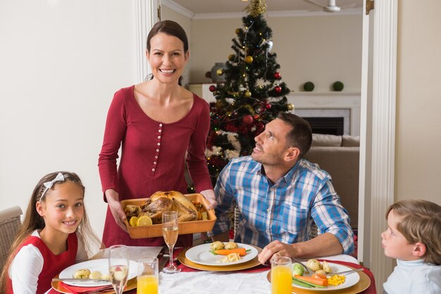 Mujer bonita que sirve pavo asado a su familia