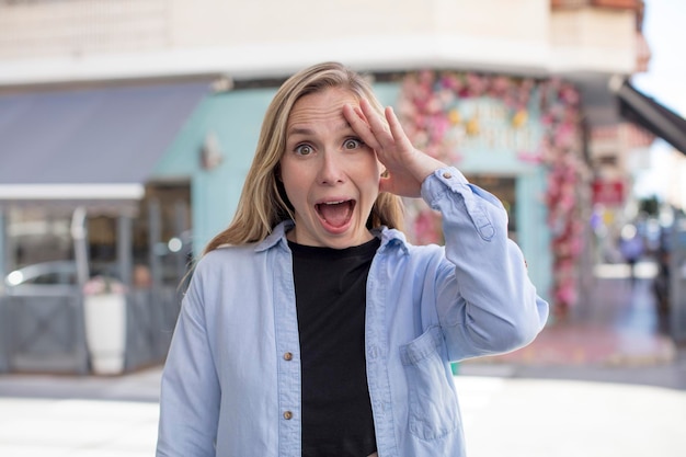 Mujer bonita que se ve feliz, asombrada y sorprendida, sonriendo y dándose cuenta de buenas noticias increíbles e increíbles.