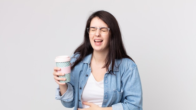 Mujer bonita riendo a carcajadas de una broma hilarante y sosteniendo un café para llevar