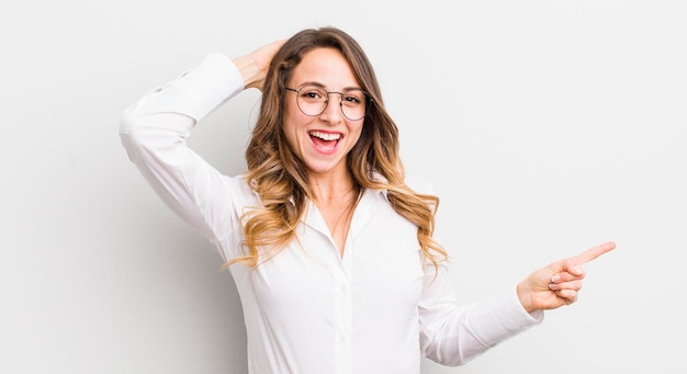 Mujer bonita riéndose feliz positiva y sorprendida al darse cuenta de una gran idea que apunta al espacio de copia lateral