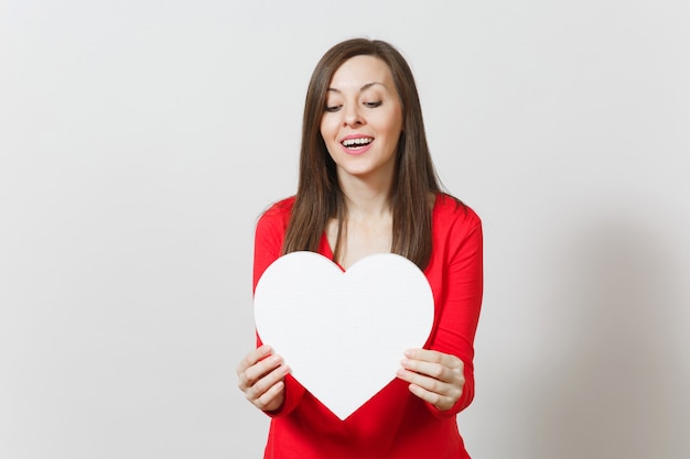 Mujer bonita en ropa roja con gran corazón blanco en manos aisladas sobre fondo blanco. Copie el espacio para publicidad. Con lugar para texto. Concepto de día de San Valentín o día internacional de la mujer.