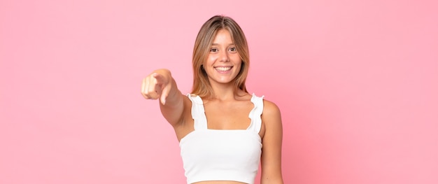 Mujer bonita rubia apuntando a la cámara con una sonrisa satisfecha, confiada y amistosa, eligiéndote