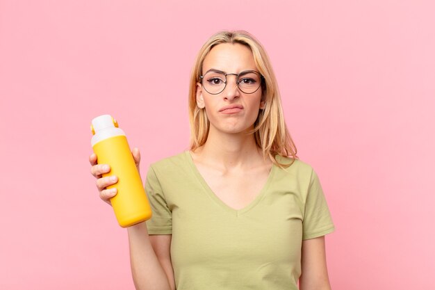 Mujer bonita rubia con un batido de naranja