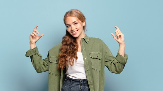 Mujer bonita rubia enmarcando o delineando su propia sonrisa con ambas manos, luciendo positivo y feliz, concepto de bienestar