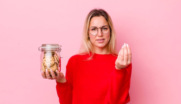 Mujer bonita rubia haciendo capice o gesto de dinero diciéndote que pagues el concepto de cookies