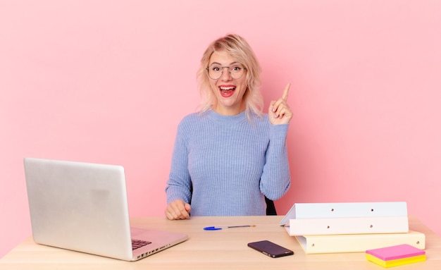 mujer bonita rubia joven mujer bonita que se siente como un genio feliz y emocionado después de darse cuenta de una idea. concepto de escritorio de espacio de trabajo