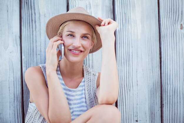 Mujer bonita rubia llamando por teléfono en el fondo de madera