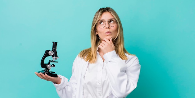 Foto mujer bonita rubia pensando sintiéndose dudosa y confundida científico y concepto de microscopio