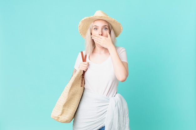 Mujer bonita rubia que cubre la boca con las manos con una sorpresa. concepto de verano