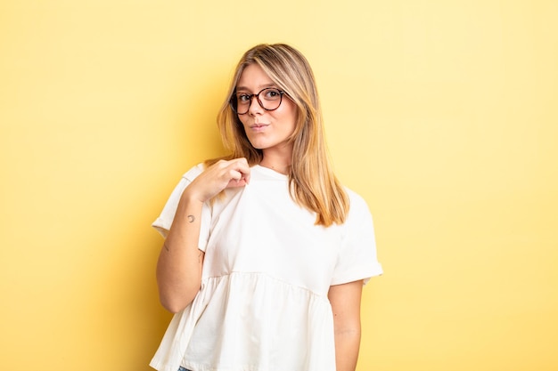 Mujer bonita rubia que parece arrogante, exitosa, positiva y orgullosa, apuntando a sí misma