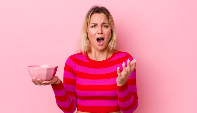 Mujer bonita rubia que parece desesperada frustrada y estresada concepto de tazón vacío