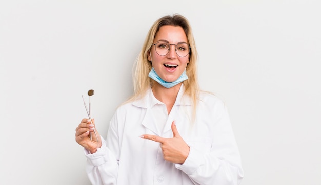 Mujer bonita rubia que parece emocionada y sorprendida apuntando hacia un lado