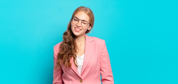 Mujer bonita rubia que parece feliz y amistosa, sonriendo y guiñando un ojo con una actitud positiva