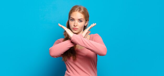 Mujer bonita rubia que parece molesta y harta de tu actitud, ¡diciendo basta! manos cruzadas al frente, diciéndote que te detengas