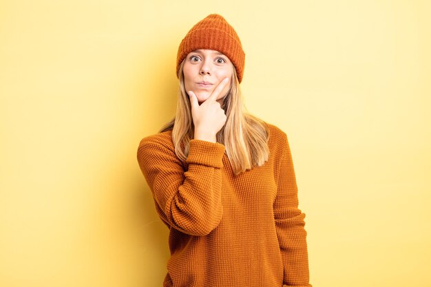 Mujer bonita rubia que parece seria, pensativa y desconfiada, con un brazo cruzado y la mano en la barbilla, opciones de ponderación