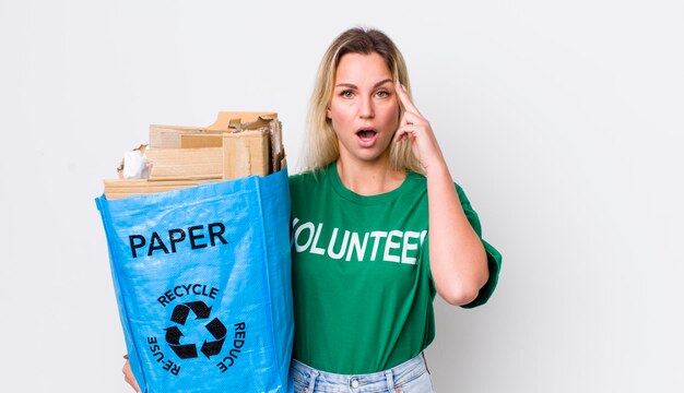 Mujer bonita rubia que parece sorprendida al darse cuenta de una nueva idea de pensamiento o concepto de reciclaje