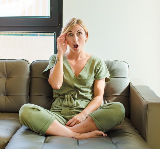 Mujer bonita rubia que parece sorprendida, con la boca abierta, conmocionada, dándose cuenta de un nuevo pensamiento, idea o concepto