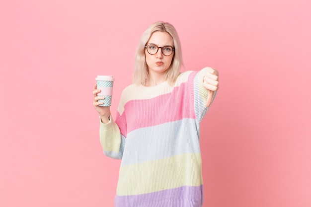 Mujer bonita rubia que se siente cruzada, mostrando los pulgares hacia abajo. concepto de cafe