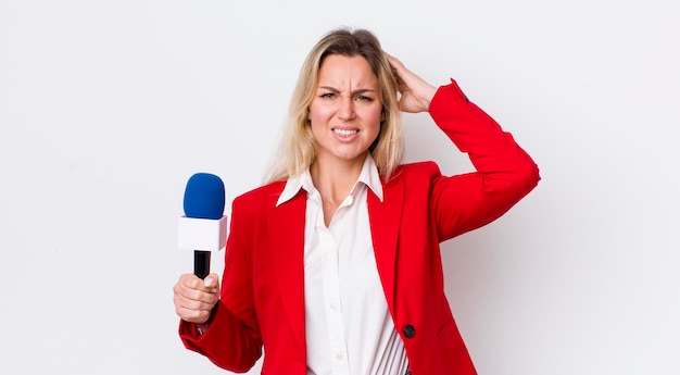 Mujer bonita rubia que se siente estresada ansiosa o asustada con las manos en la cabeza y el concepto de micrófono