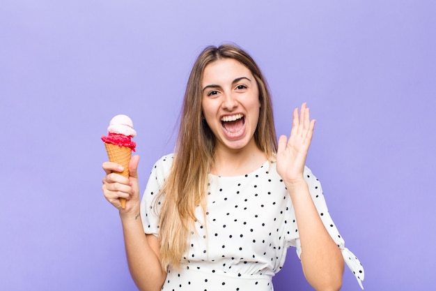 Mujer bonita rubia que se siente feliz, emocionada, sorprendida o conmocionada, sonriendo y asombrada por algo increíble