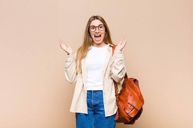 Mujer bonita rubia que se siente feliz, emocionada, sorprendida o conmocionada, sonriendo y asombrada por algo increíble