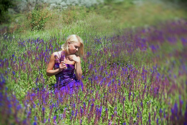 Mujer bonita rubia recogiendo flores de color púrpura