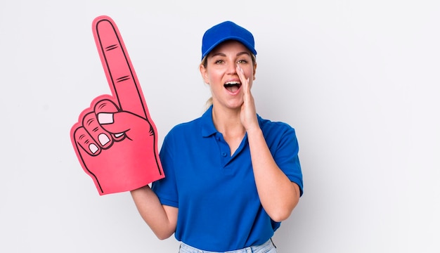 Mujer bonita rubia sintiéndose feliz dando un gran grito con las manos al lado de la boca concepto de ventilador de mano número uno