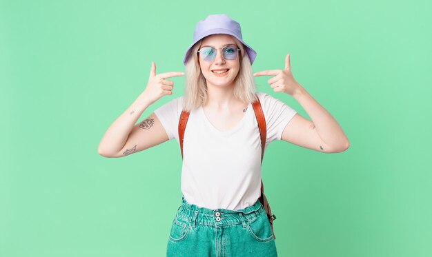 Mujer bonita rubia sonriendo con confianza apuntando a su propia amplia sonrisa. concepto de verano