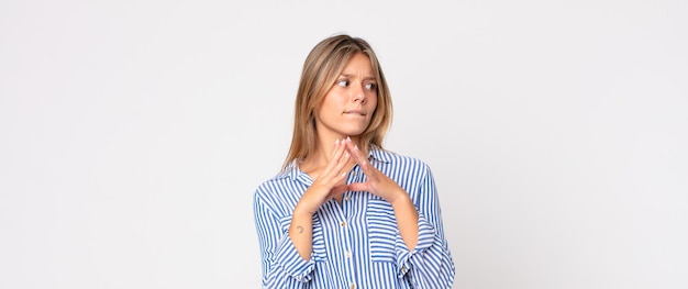 Mujer bonita rubia sonriendo, disfrutando de la vida, sintiéndose feliz, amigable, satisfecha y despreocupada con la mano en la barbilla