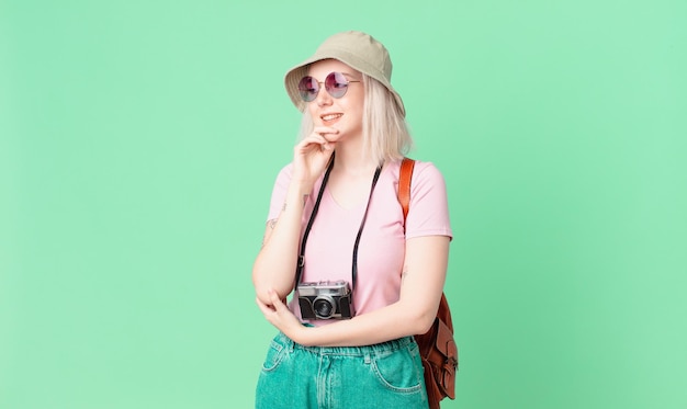 Mujer bonita rubia sonriendo con una expresión feliz y segura con la mano en la barbilla. concepto de verano