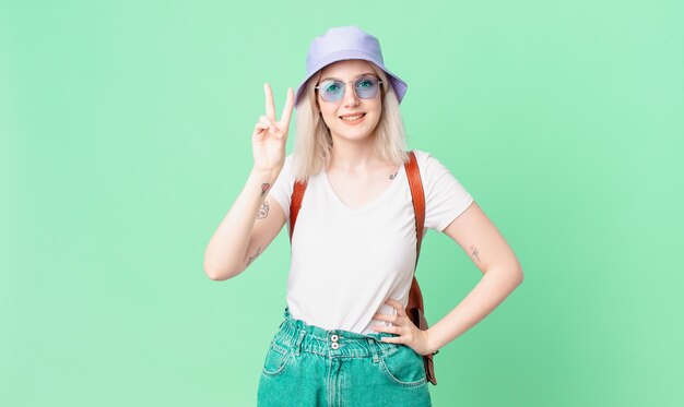 Mujer bonita rubia sonriendo y luciendo amigable, mostrando el número dos. concepto de verano